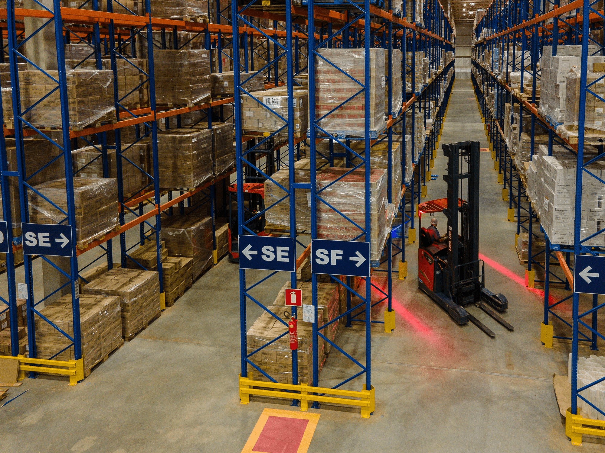 View from the second floor of the warehouse on a forklift moving among racks with pallets