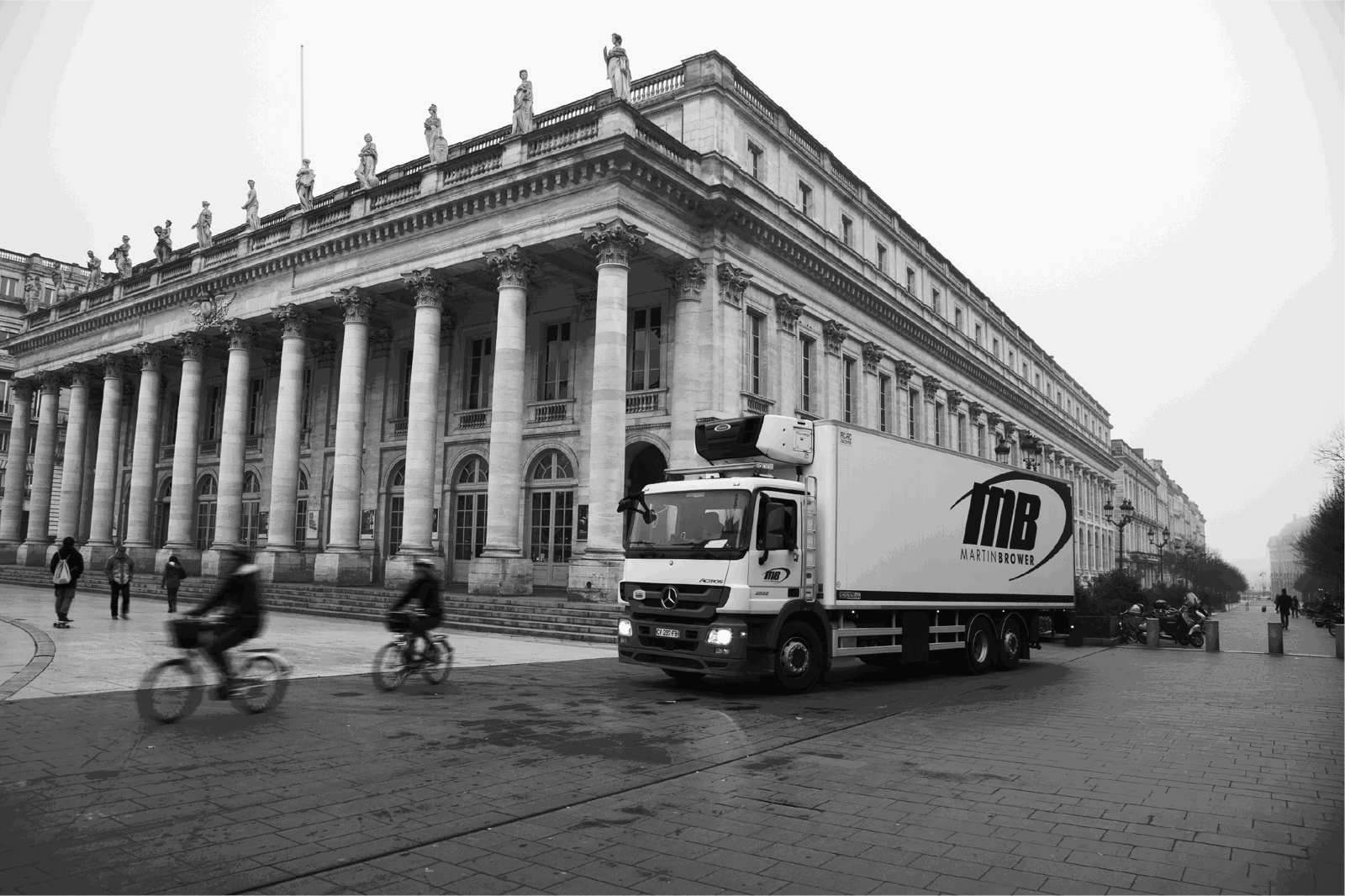 Black and white photo of a Martin Brower truck driving against the background of a building