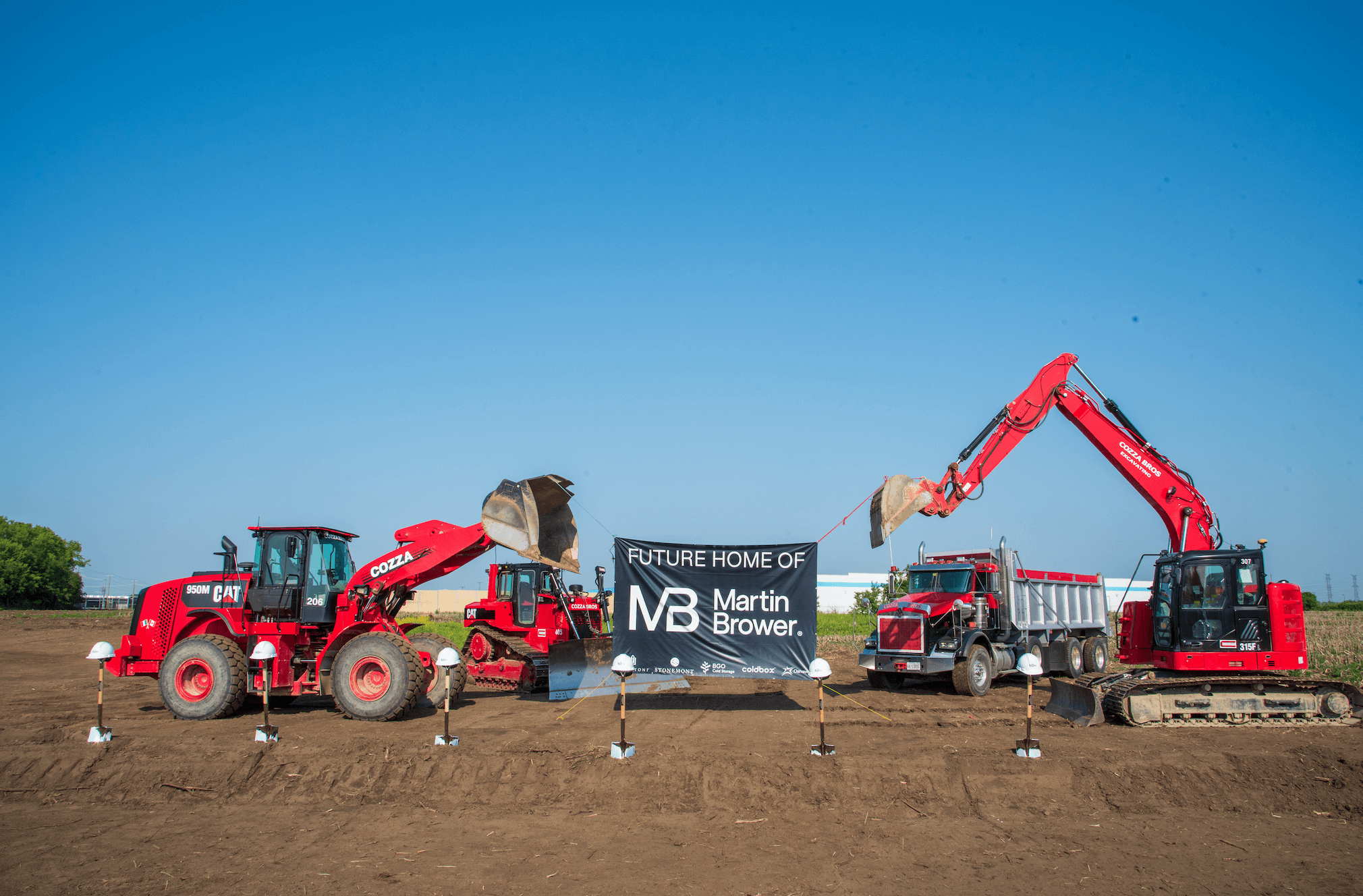 Excavators with buckets holding Martin Brower banner