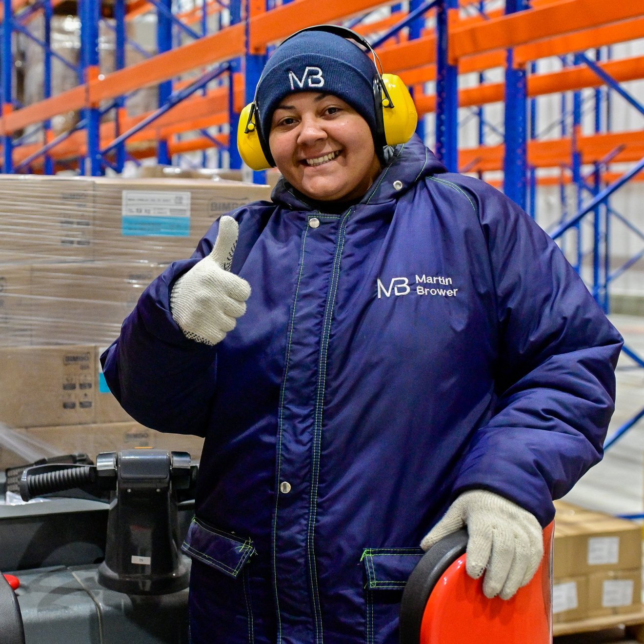 Smiling woman in warehouse with thumb up