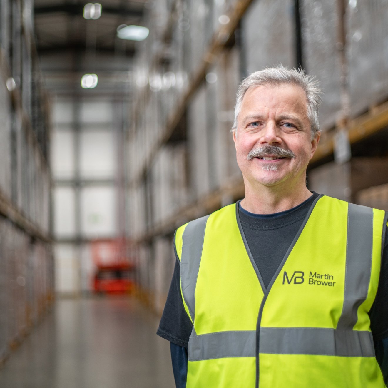 Smiling man wearing a high visibility vest in a warehouse