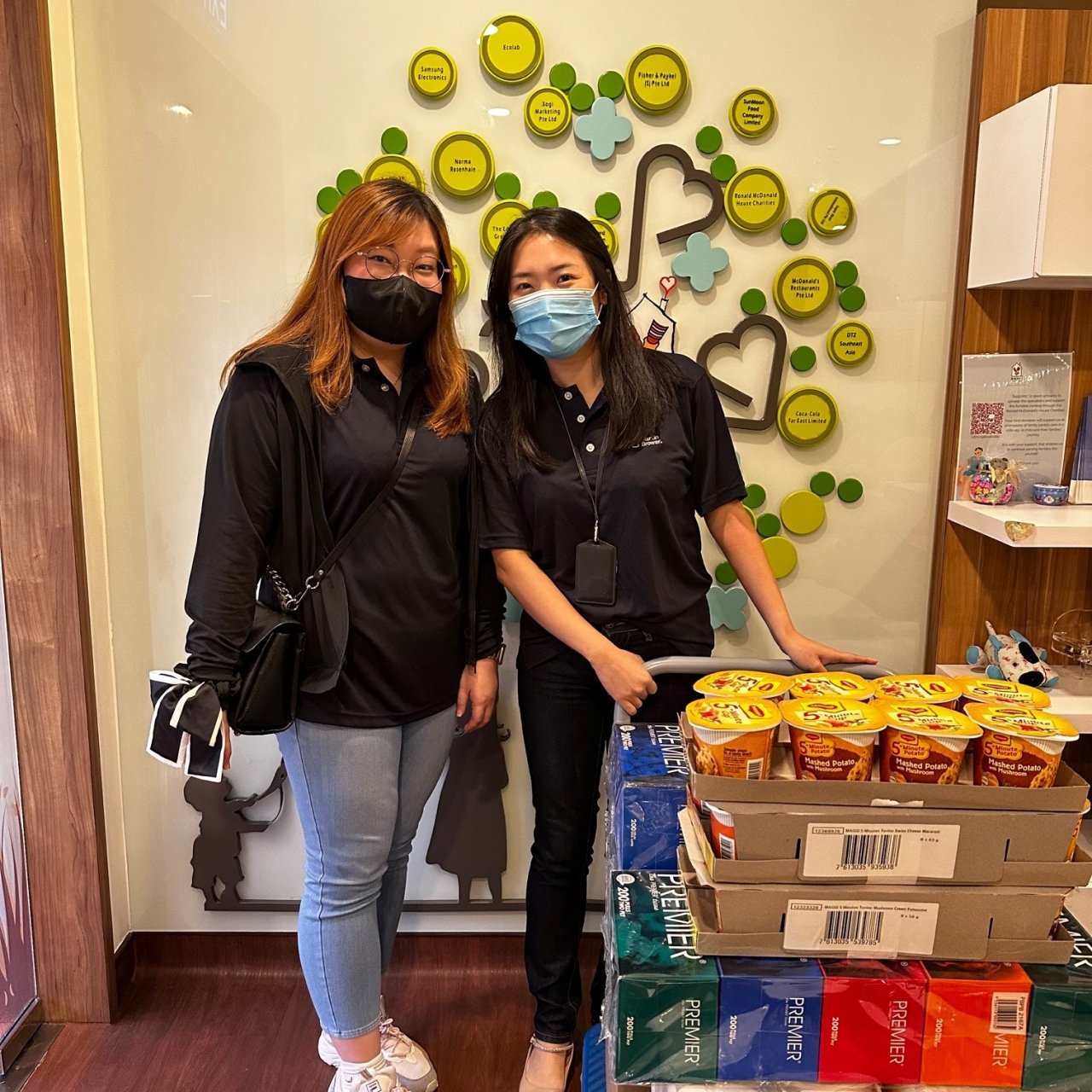 Two women in masks with a cart full of food intended for donations