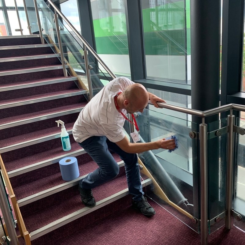 Man cleaning glass stairwell piece