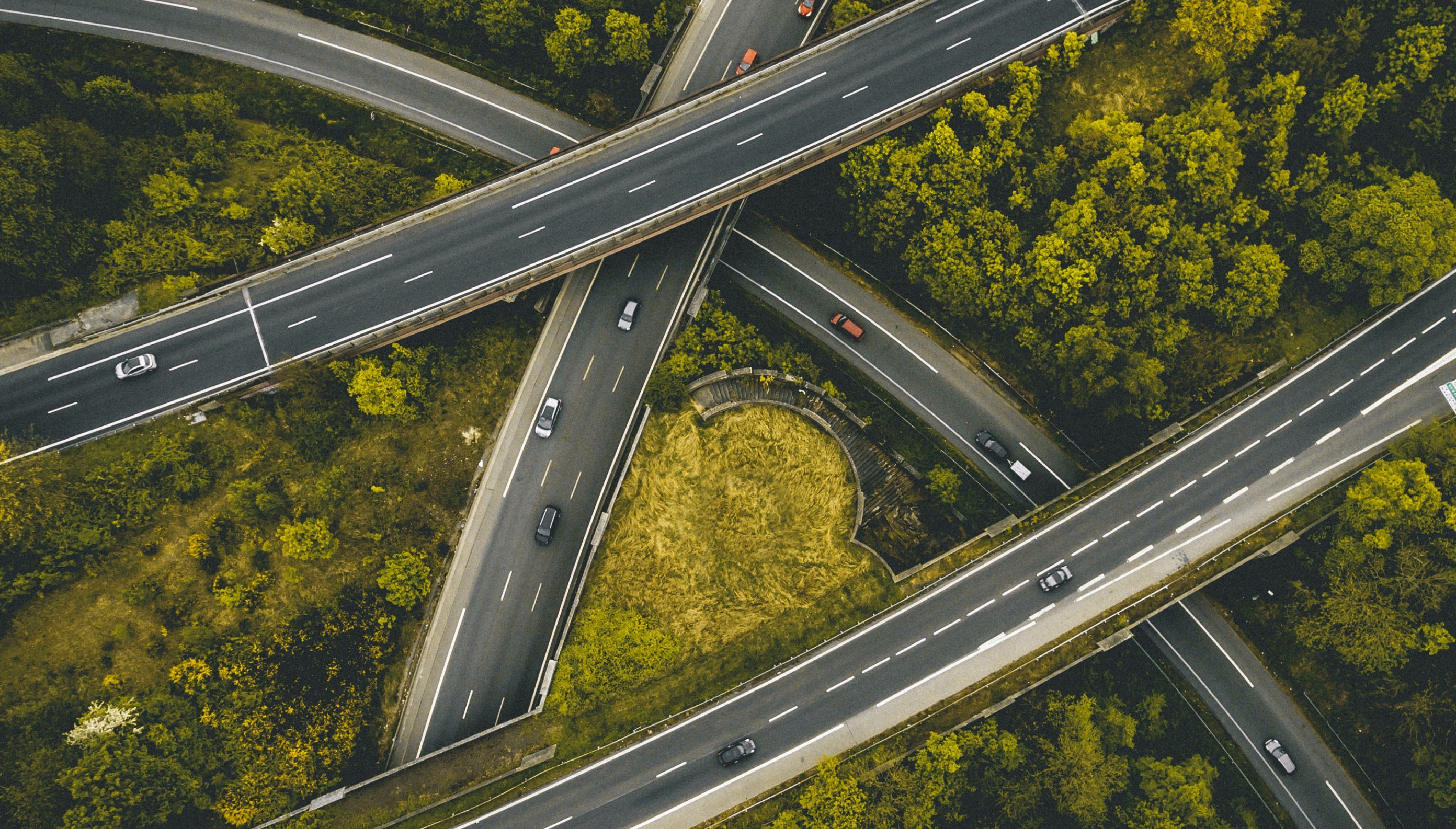 Aerial image of highway with cars driving and trees surrounding it